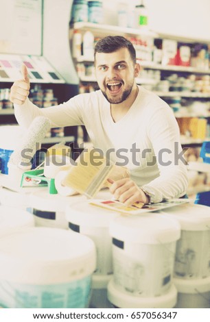 Smiling male customer purchasing tools for house improvements in paint supplies store