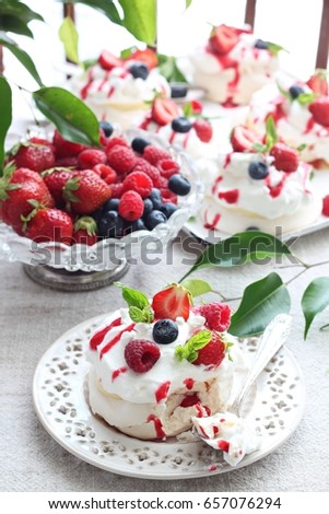 Pavlova dessert with raspberries , blueberries and strawberries on top 