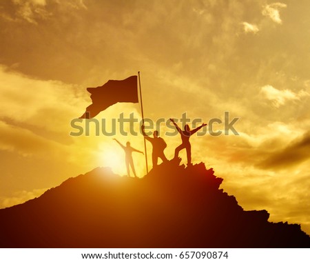 The conquest of the summit, three silhouette families, the father of mother and child, the flag of victory on the top of the mountain, hands up. A man on top of a mountain. Against the evening sky Royalty-Free Stock Photo #657090874