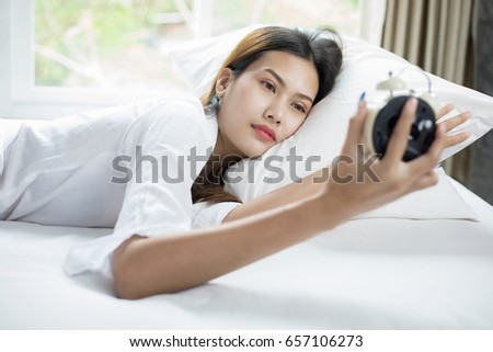 asian woman happy waking up and turning off the alarm clock having a good day