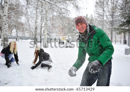Group of young people playing outdoor snowballs in winter forest
