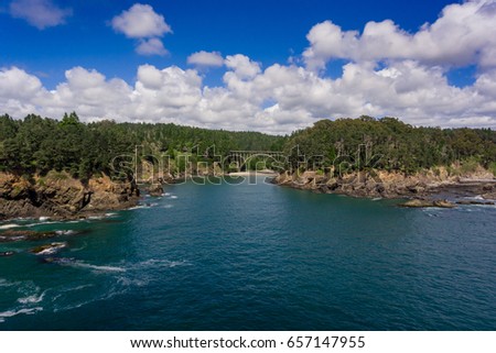 Russian Gulch State Park, Northern CA - aerial view of bridge under a stunning blue sky, with puffy white clouds with the forest and blue pacific ocean surrounding