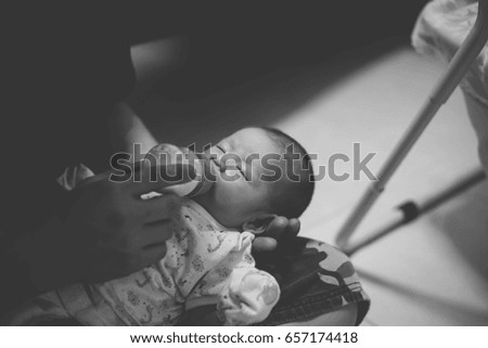 Dad take care baby by feeding milk and baby have comfortable and sleepy, in black and white picture.