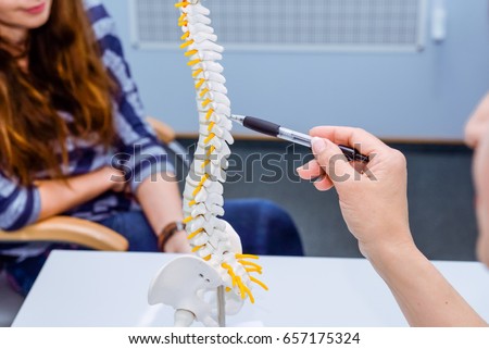 Closeup medical doctor woman pointing on spine model and explaining female patient her problem. Healthcare concept Royalty-Free Stock Photo #657175324