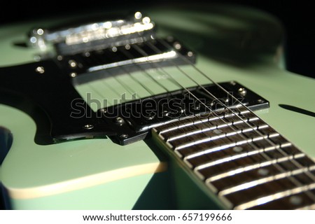 Shallow depth of field macro lens shot of vintage electric guitar lit by the sun.  Close up of old electric guitar neck, bridge, and pickups, 6 string electric guitar.