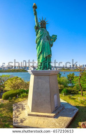 Urban landscape of Statue of Liberty and Rainbow Bridge, icons of Odaiba Island in Tokyo, Japan. Replica of famous Statue of Liberty of New York. Tokyo cityscape on background. Vertical shot.