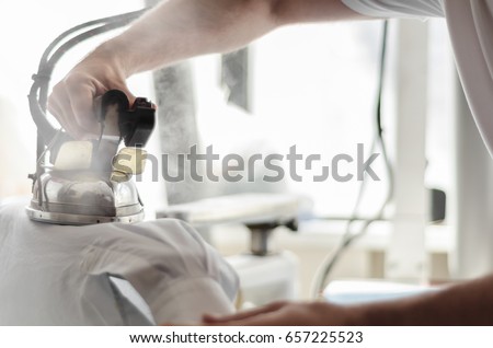 hand ironing in store or fabric Royalty-Free Stock Photo #657225523