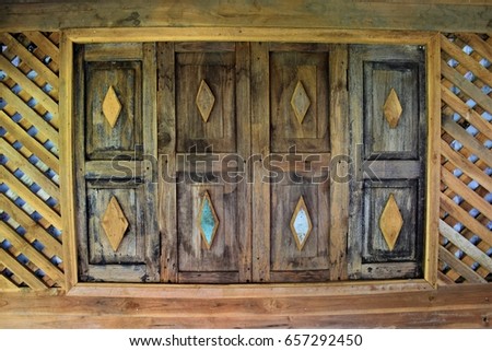 Thai style wood windows in brown color from old house Royalty-Free Stock Photo #657292450