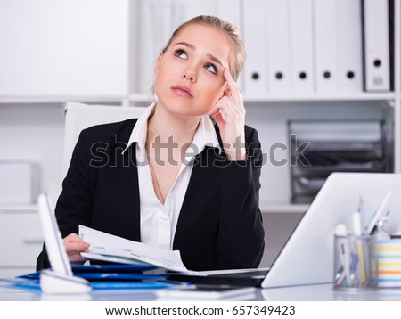 Portrait of upset businesswoman with headache working with documents in office