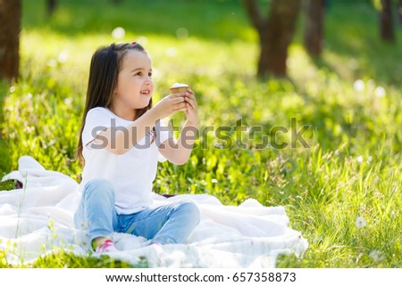 Child eating ice cream. Little girl on the grass with ice creamChildren eat icecream. Little girl with vanilla ice cone.