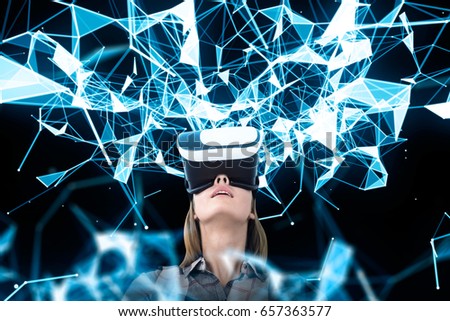 Portrait of a young woman wearing VR glasses and looking upwards at an abstract blue pattern against a black wall.