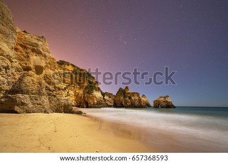 Night panorama with stars on the sky of a coast of Praia da Rocha in Portimao, Algarve region, Portugal