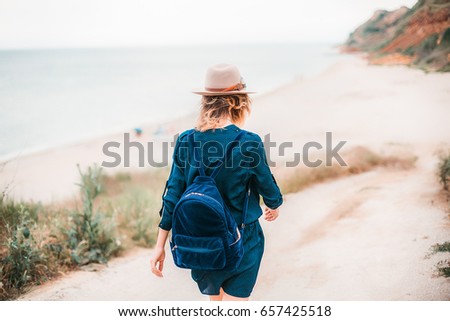Back summer portrait of young woman in brown hat having fun on the sea.slim beautiful woman,bohemian outfit,indie style,summer vacation,positive,romantic,girl in a dress,attractive,dreamer,bag,joy