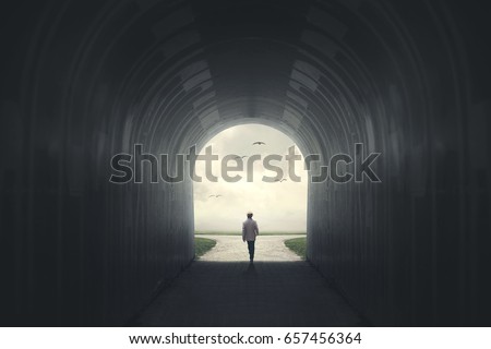 Man getting out from a dark tunnel Royalty-Free Stock Photo #657456364