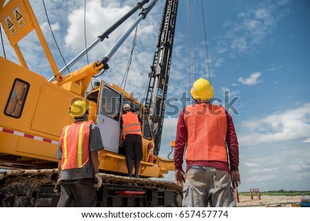 Engineer and foreman looking at heavy machine Assembly concrete pile driving truck  for  working against building construction crane Royalty-Free Stock Photo #657457774