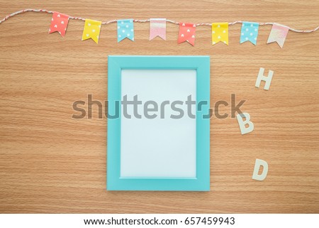 Flat lay of photo frame with happy birthday wooden alphabet mockup on wooden table