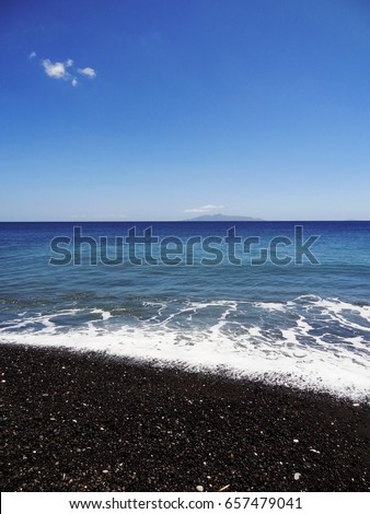 Portrait view of Kamari Beach with black sand opposite the Anafi island, Santorini, Cyclades, Aegean Sea, Greek island, Greece