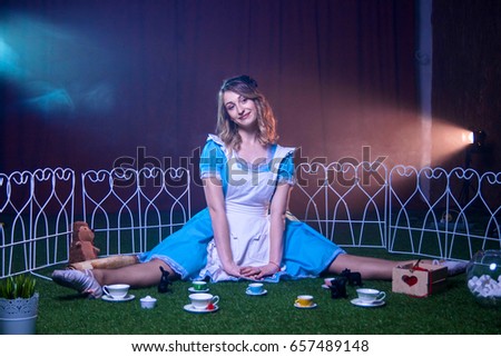 Lovely happy Alice sits on a glade in Wonderland