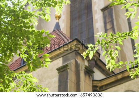 Detail of historic old church i Prague, view through beautiful green treetops. Architecture close up in Prague. Kostel Sv. Antonína Paduánského - Church of Saint Antonin Paduansky, Prague.