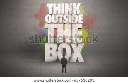 Colorful wall with illustrated quote saying think outside the box for a small businessman standing in grey urban space concept