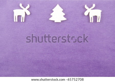 two white vilt reindeers next to a white felt christmas tree in the middle on a deep purple paper background