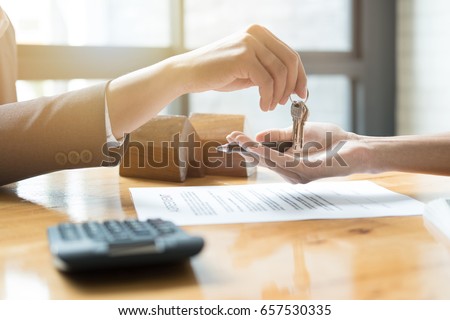 estate agent giving house keys to man and sign agreement in office Royalty-Free Stock Photo #657530335