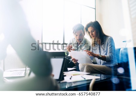 Teamwork concept.Young business people working with new startup project.Mobile devices on table,documents and marketing reports.Blurred background,visual effect,flare.Horizontal
