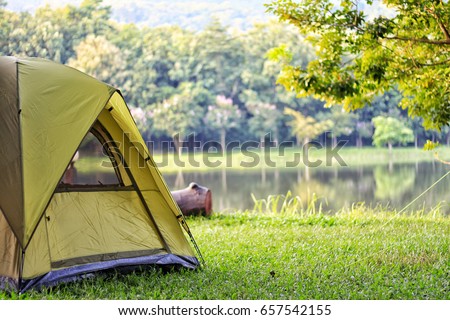 Camping green tent in forest near lake Royalty-Free Stock Photo #657542155