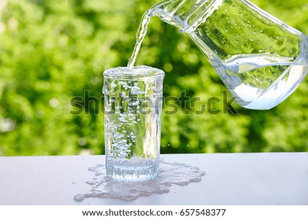 overflowing water in a glass Outdoors in summer Royalty-Free Stock Photo #657548377