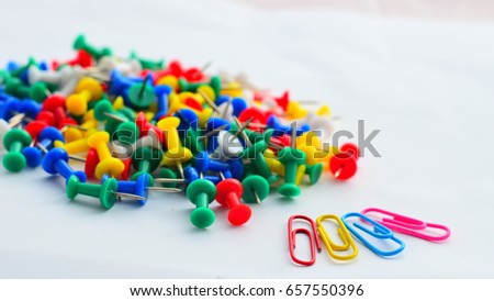 Colorful pins with paper clips on white paper background, Focusing on paper clip.