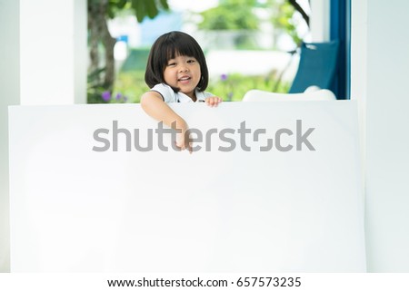 Smiling happy Asian little girl with big white poster on park.