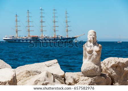 View with stone sculpture of a mermaid in city of Piran and large sailing ship on background, Slovenia.