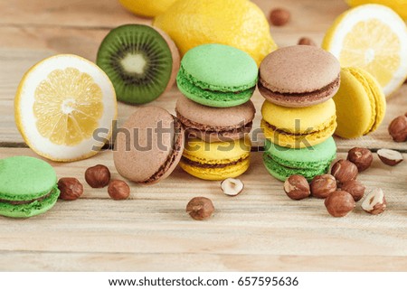 Green, yellow and brown french macarons with lemon, kiwi and hazelnuts, soft focus background