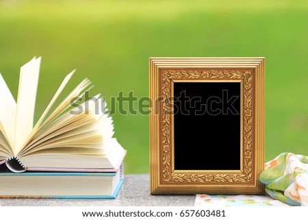 Golden frame with books on wooden table