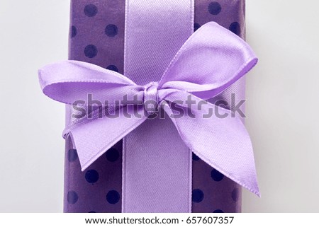 Cropped picture of gift box. Purple ribbon on violet box, white background.