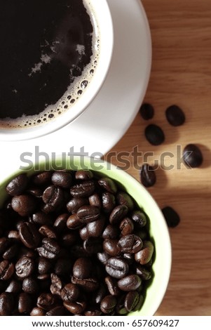 Top view, Coffee beans in cup with a cup of coffee on wooden table