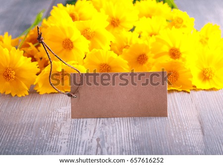 Yellow flowers and tag on wooden table