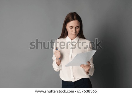Businesswoman holds the papers in her hands and reads what is written there. Isolated on gray background.