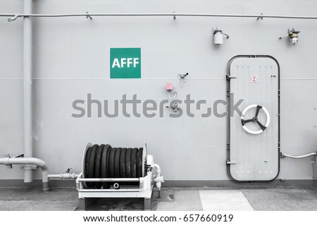 Roll of Fire hose front of battleship entrance door background