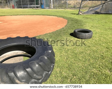 Baseball field with old tires and training equipment.