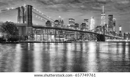 Black and white photo of Brooklyn Bridge and Manhattan at night, New York City, USA.
