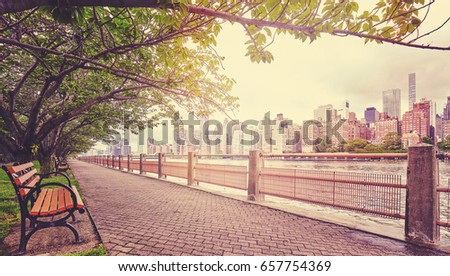 Color toned picture of a promenade in Roosevelt Island with Manhattan view, focus on buildings, New York City, USA.