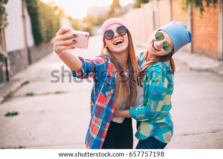 Two cheerful young woman are photographed on a mobile phone