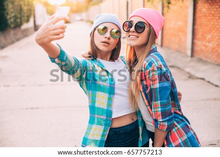 Two cheerful young woman are making selfie on a mobile phone