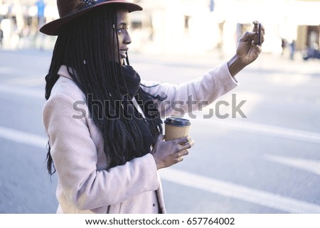 Attractive afro american hipster girl dressed in trendy casual wear posing for taking photo for social networks, female black model making selfie for blogging via modern smartphone and 4G connection