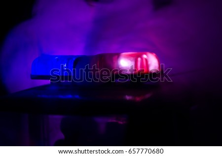 Red light flasher atop of a police car. City lights on the background.