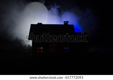 Old house with a Ghost in the moonlit night or Abandoned Haunted Horror House in fog. Old mystic villa with surreal big full moon. Horror Halloween concept.