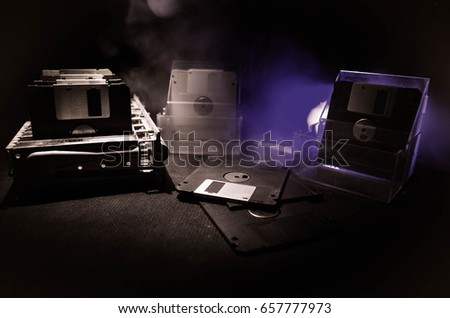 Pile of black floppy disks (diskette) on dark background with light
