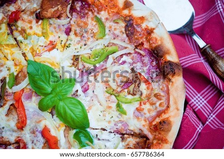 Italian pizza with tomato topped with golden melted cheese, herbs and basil served on a round wooden plank on an old wooden table
