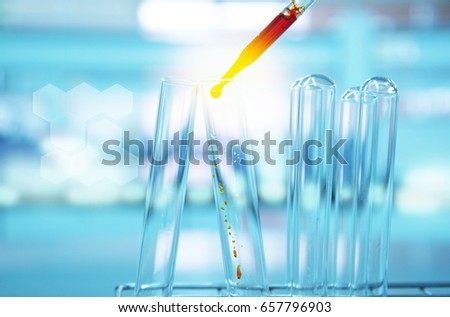 orange drop with glass test tube in science laboratory with blue light background and chemical structure 